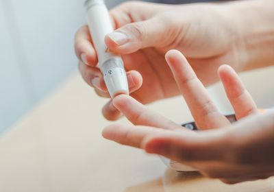 Close-up of women&rsquo;s hands using lancet on finger.