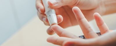 Close-up of women&rsquo;s hands using lancet on finger.